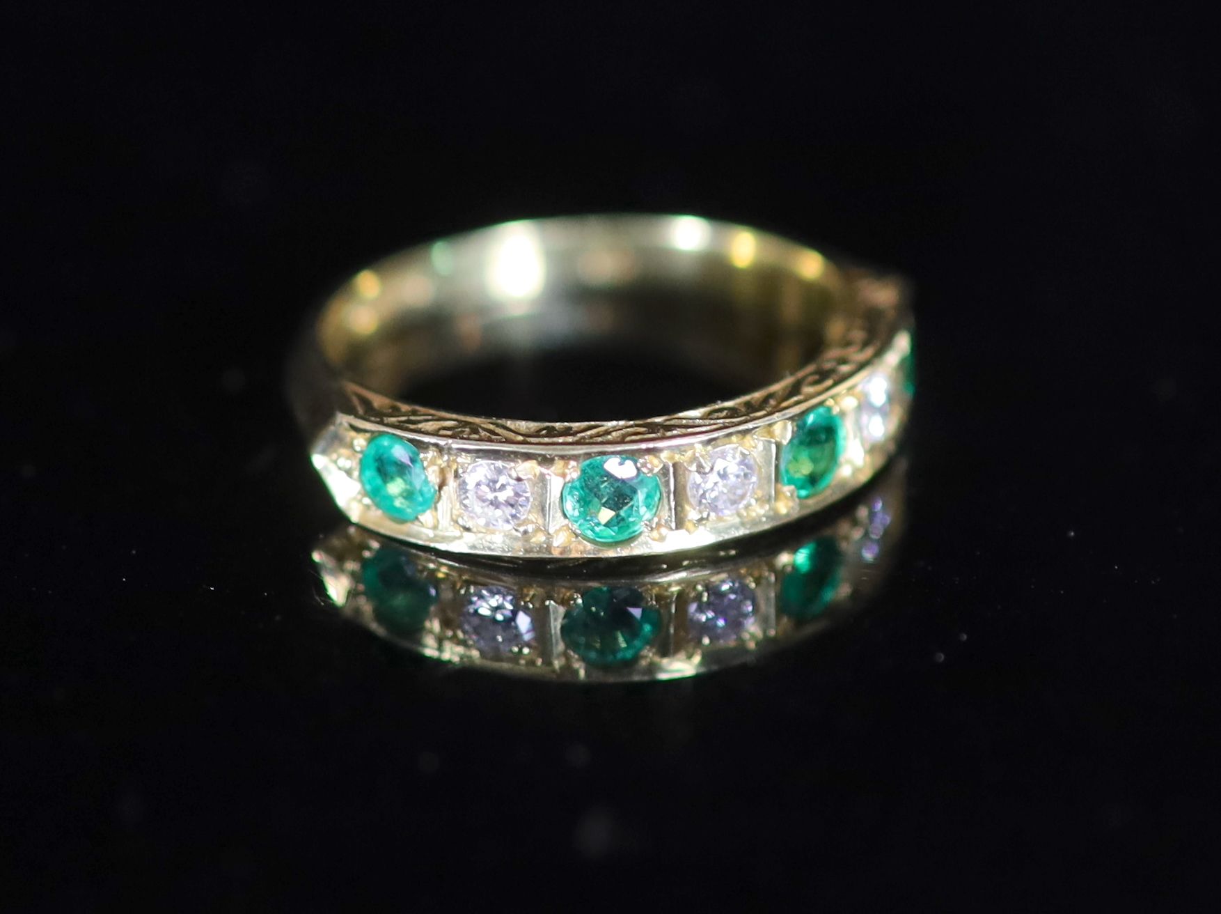 A modern 18ct gold, four stone emerald and three stone diamond set half hoop ring